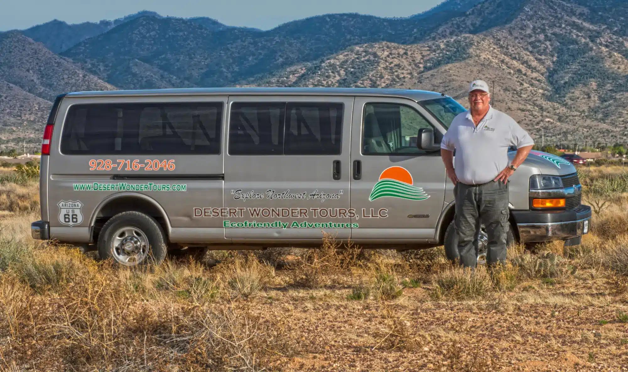 Robert Walton of Desert Wonder Tours stands with a tour van in a beautiful desert area